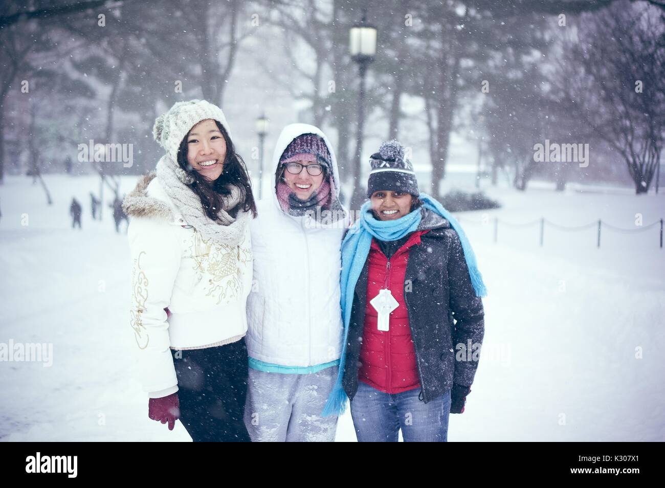 Drei Studentinnen im Schnee gang Lächeln gekleidet und für ein Foto im Schnee mit Arme umeinander gewickelt darstellen, während einer Snow Day an der Johns Hopkins University, Baltimore, Maryland, 2016. Stockfoto