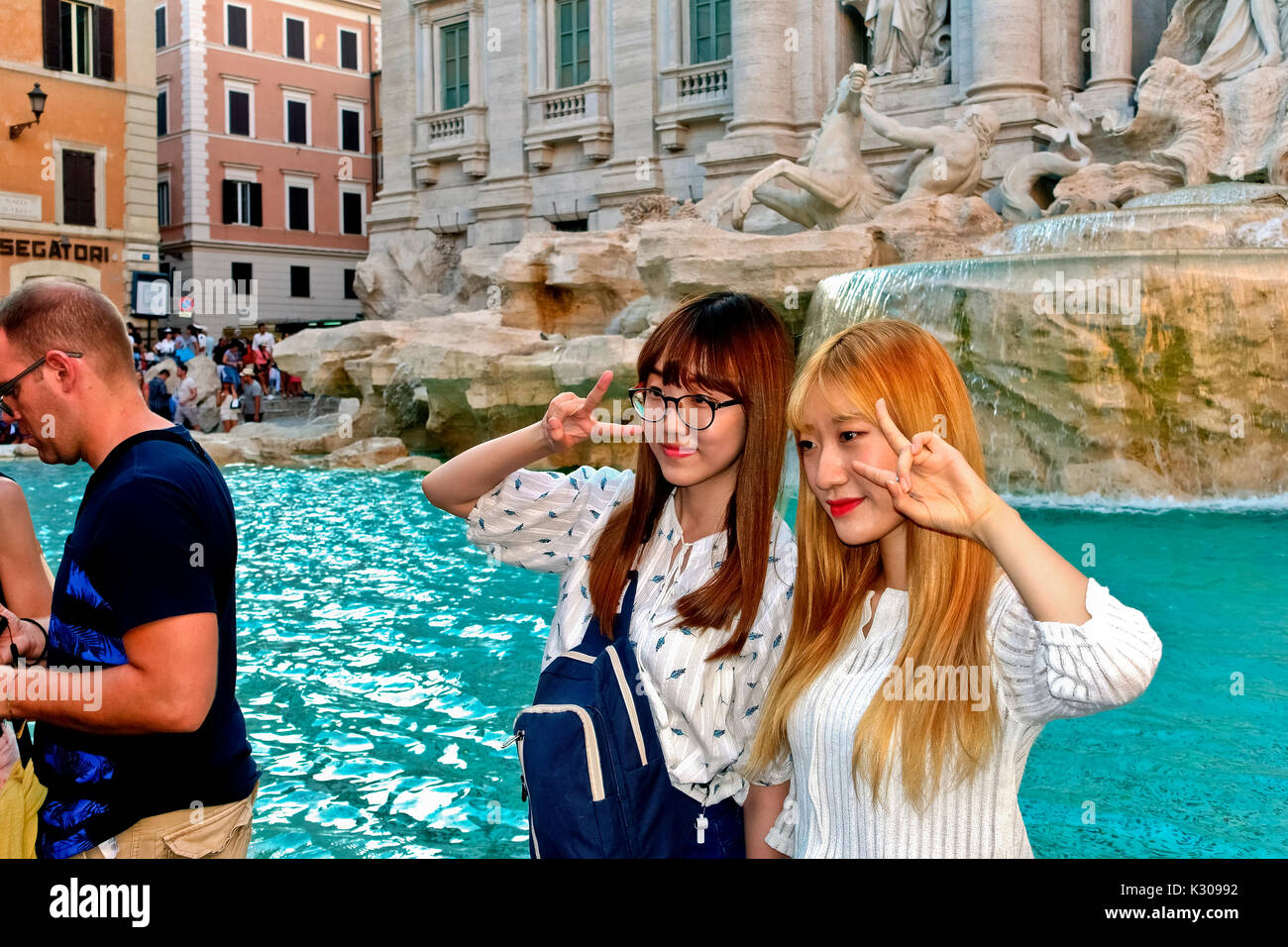 Zwei junge japanische Frauen posieren für ein Foto vor dem Trevi-Brunnen. Eine Frau mit gebleichtem Haar. Touristen, Freunde auf Reisen. Rom, Italien Europa Stockfoto
