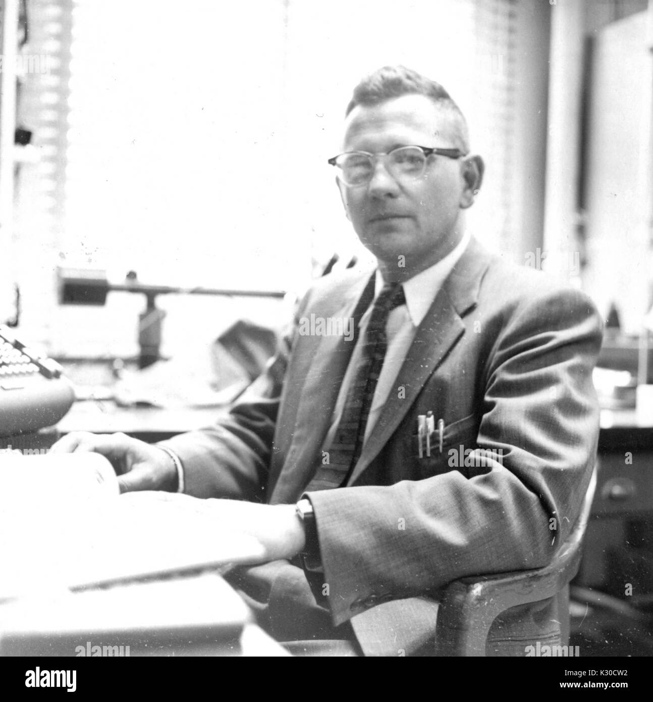 Francis Dewey Carlson, international bekannten Professor für Biophysik an der Johns Hopkins University, sitzt in seinem Büro an seinem Schreibtisch, in Anzug und Brille, Baltimore, Maryland, 1959. Stockfoto