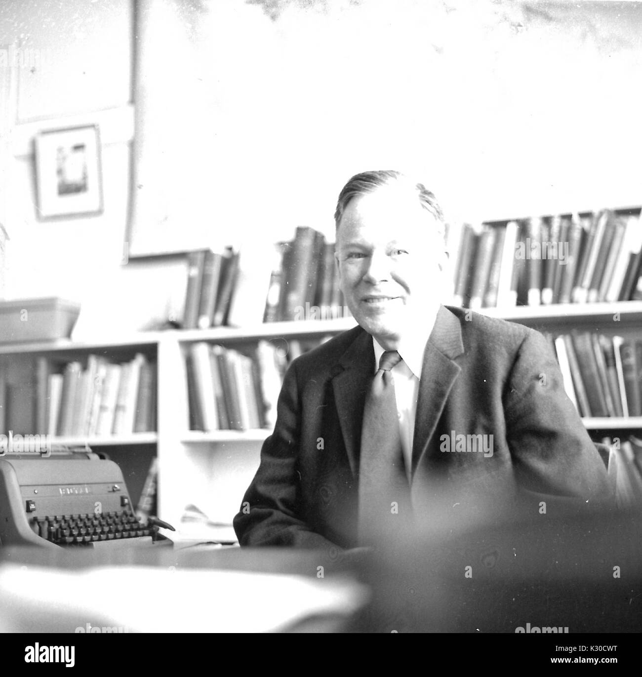 George Francis Carter, Professor für Geologie an der Johns Hopkins University und der Chesapeake Bay Gelehrter, sitzt an seinem Schreibtisch vor einer Wand von Büchern und eine Schreibmaschine, lächelnd, Baltimore, Maryland, 1959. Stockfoto