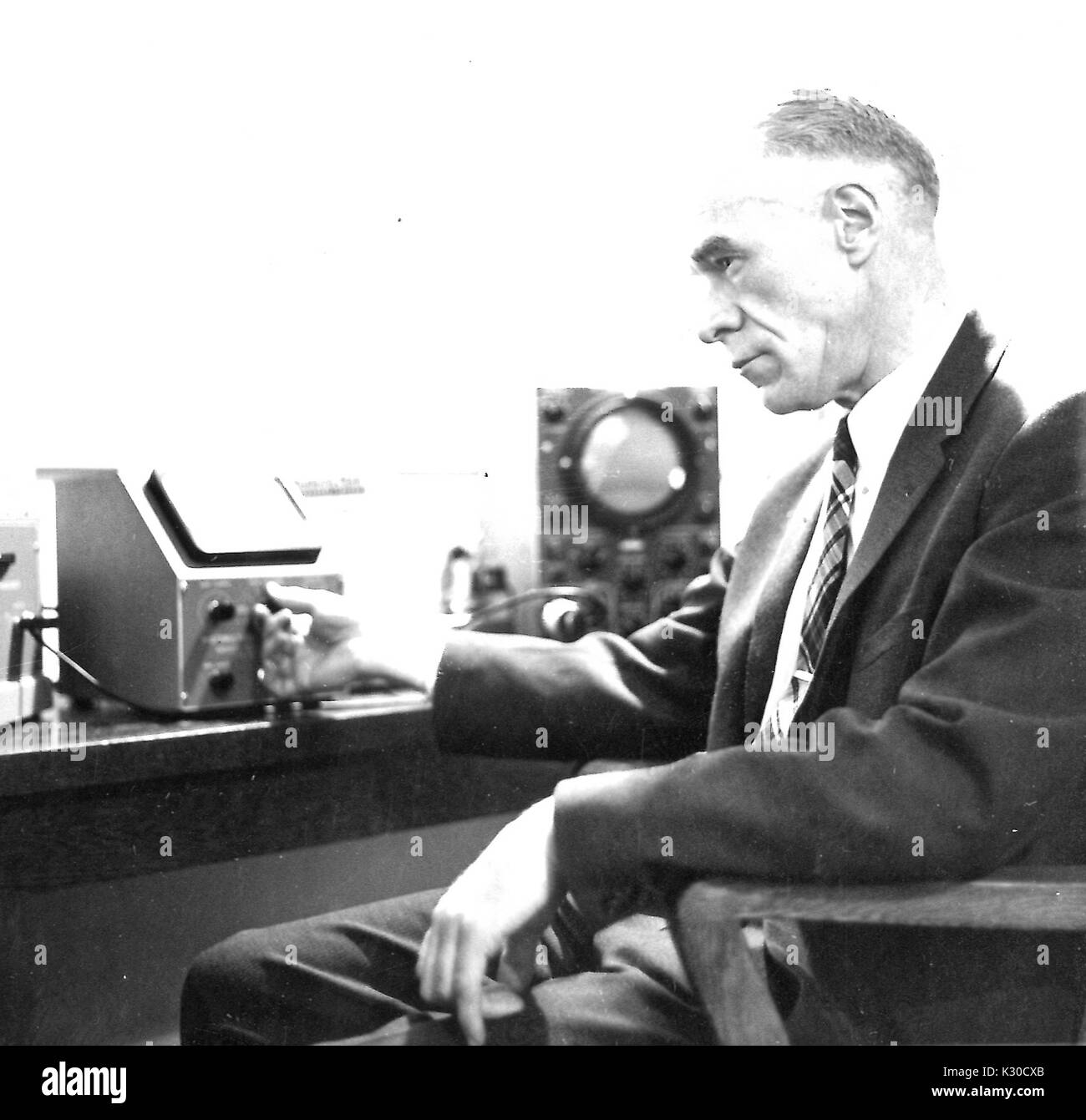 Alsoph Henry Corwin, Professor für Chemie und Abteilung Vorsitzender an der Johns Hopkins University, sitzt auf einem Stuhl in seinem Büro, während er auf ein Instrument von Laborgeräten, intensiv konzentrieren, Baltimore, Maryland, 1959. Stockfoto