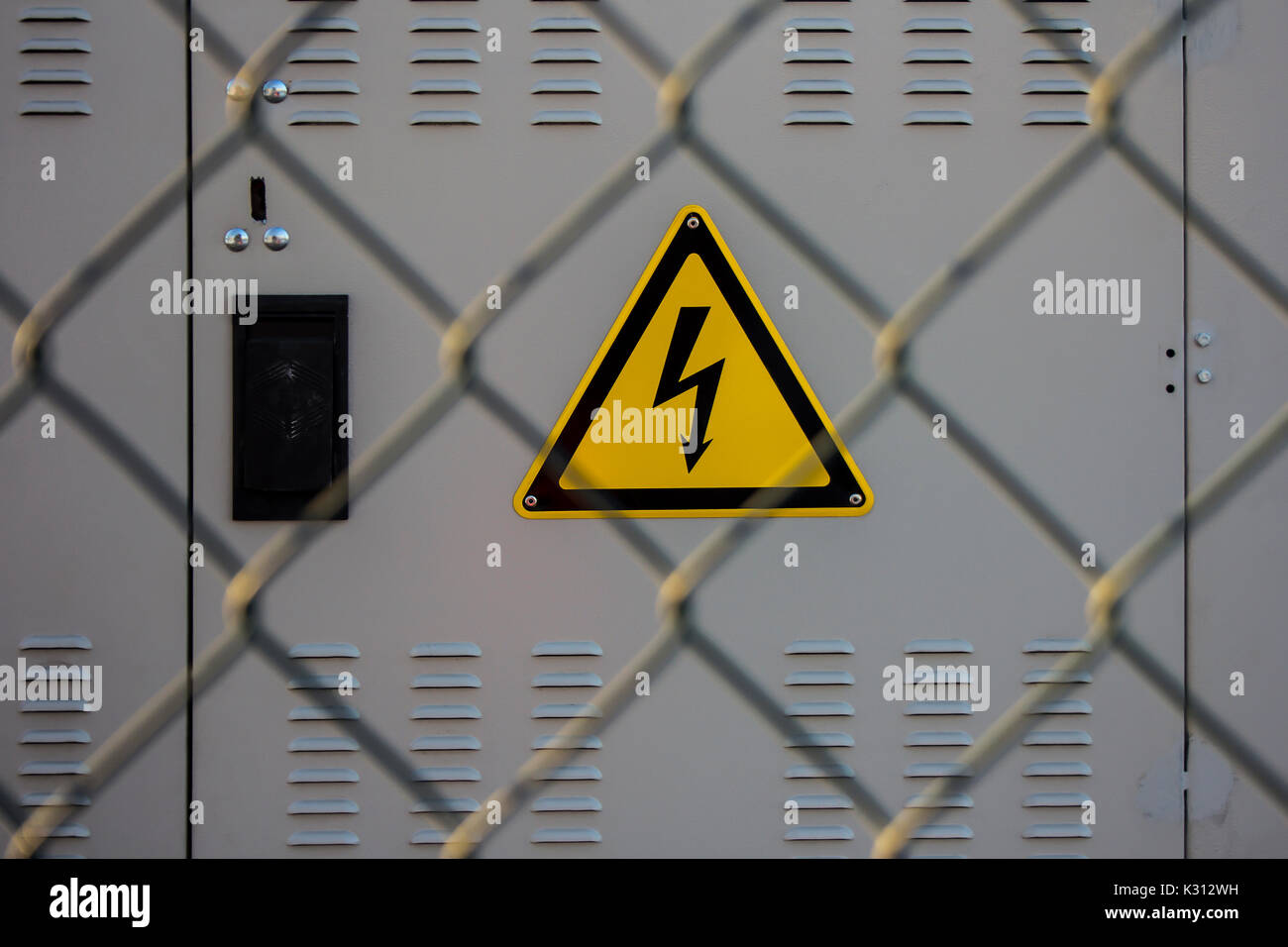 Elektrische Gefährdung Zeichen auf einer elektrischen Unterstation hinter einem Metallzaun aus Drahtgitter platziert Stockfoto