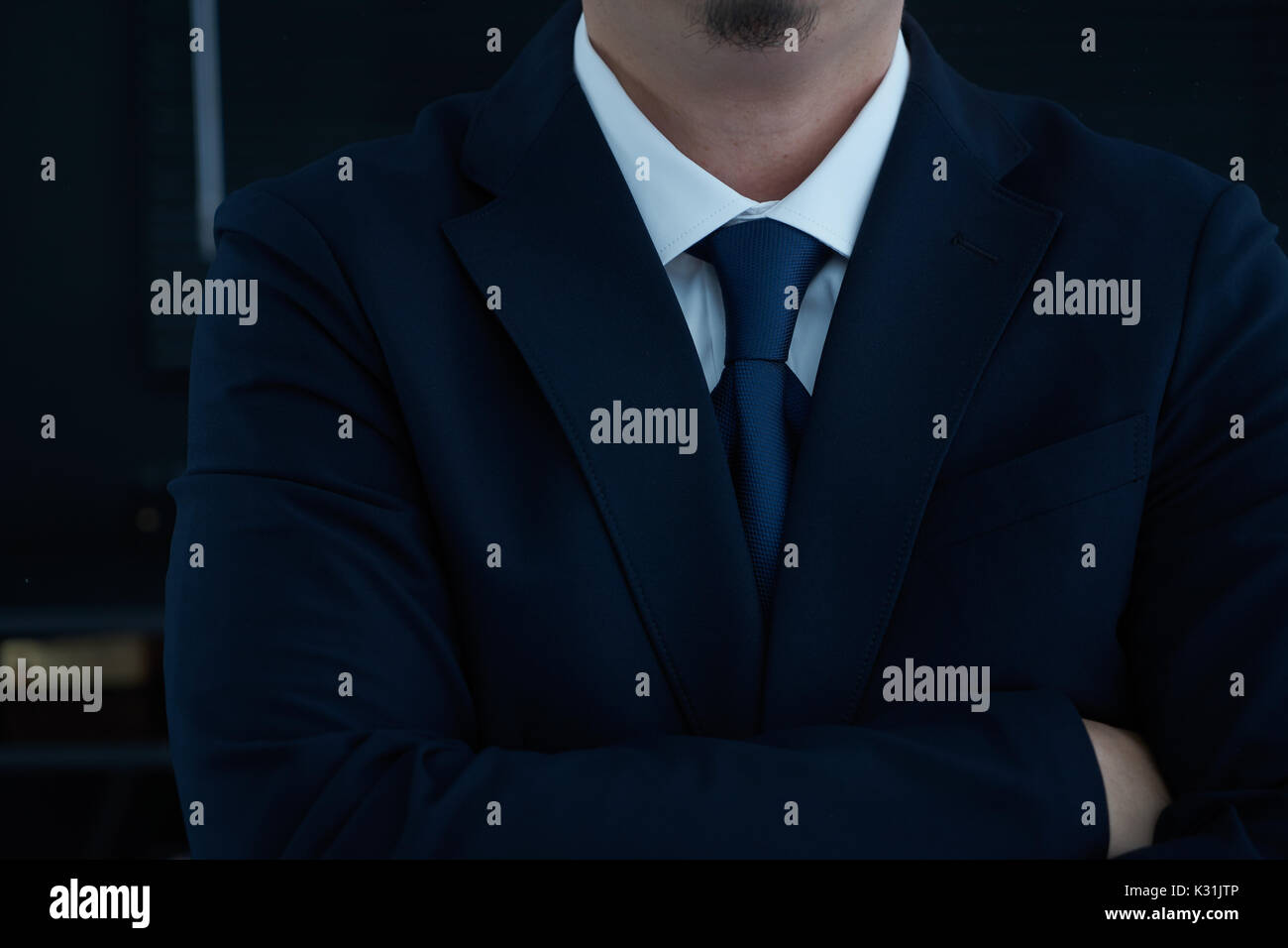 Teil des Menschen Körper Seite verschränkte seine Arme im schwarzen Anzug auf schwarzem Hintergrund, Geschäftskonzept. Stockfoto