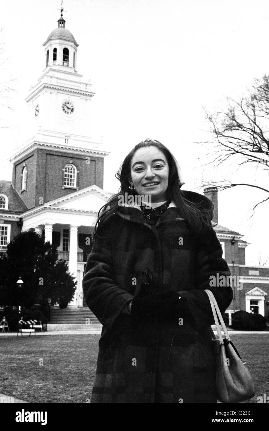 Eine weibliche Schulabgänger an der Johns Hopkins University, das Tragen von Wintermantel und Handschuhe, stellt für Ihr Foto vor Gilman Hall, eine Geistes- und Naturwissenschaften Gebäude auf dem Campus, Baltimore, Maryland, 1975. Stockfoto