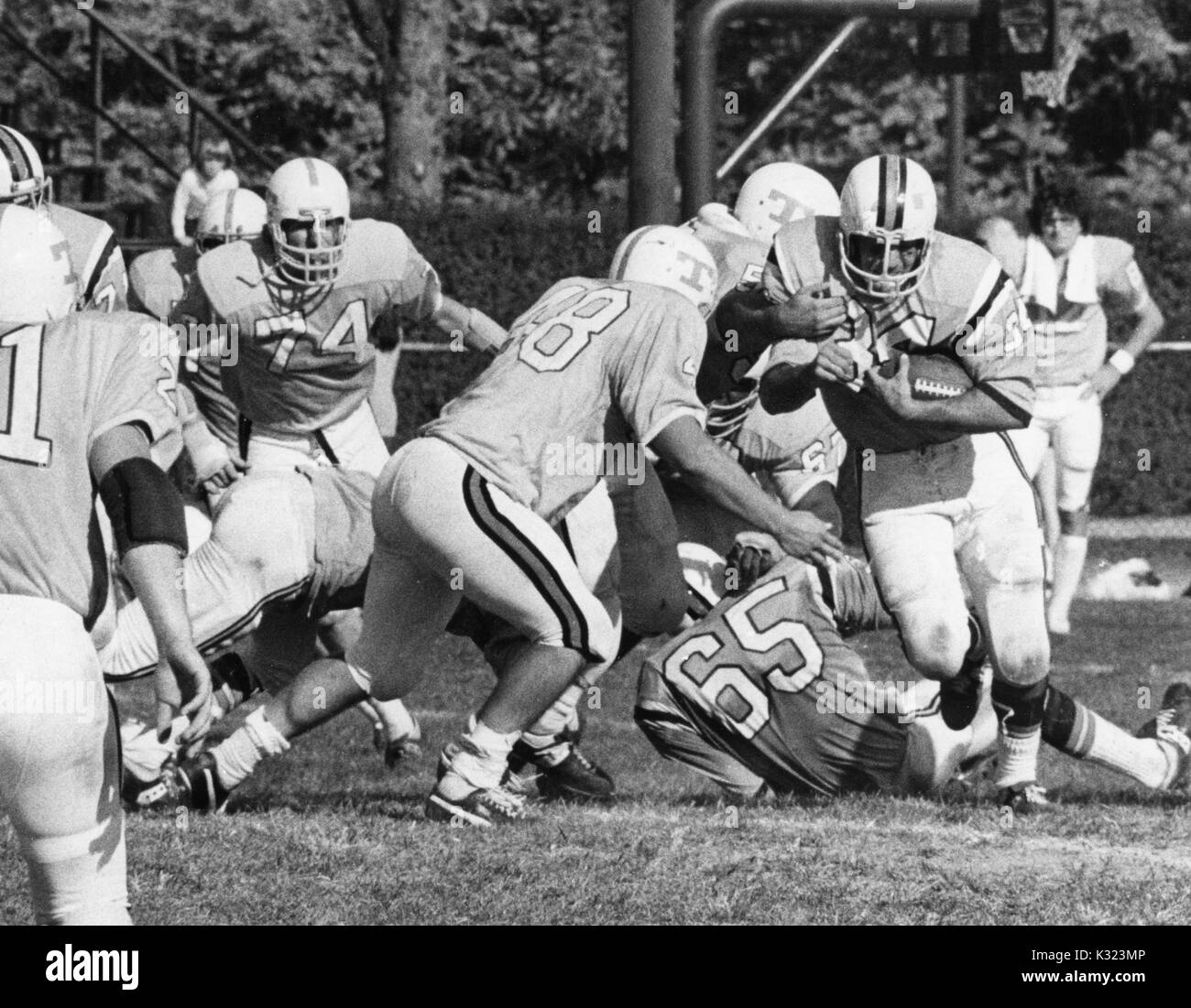 Ein Johns Hopkins University football player läuft mit dem Fußball-Vergangenheit Menschen angegangen, als Spieler der gegnerischen Mannschaft schließt in ihm an der Johns Hopkins University, Baltimore, Maryland, 1980 in Angriff zu nehmen. Stockfoto