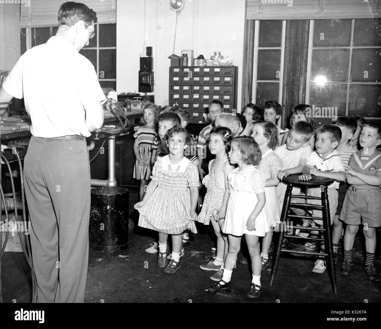 Studenten in den Kindergarten Klasse eines elementaren Demonstration school der Johns Hopkins University und in Faszination während ein glasbläser auf einem Stück mit seinem Rücken arbeitet, während ein Sommer Ausflug zu einer Glasbläserei studio, Juli, 1950. Stockfoto