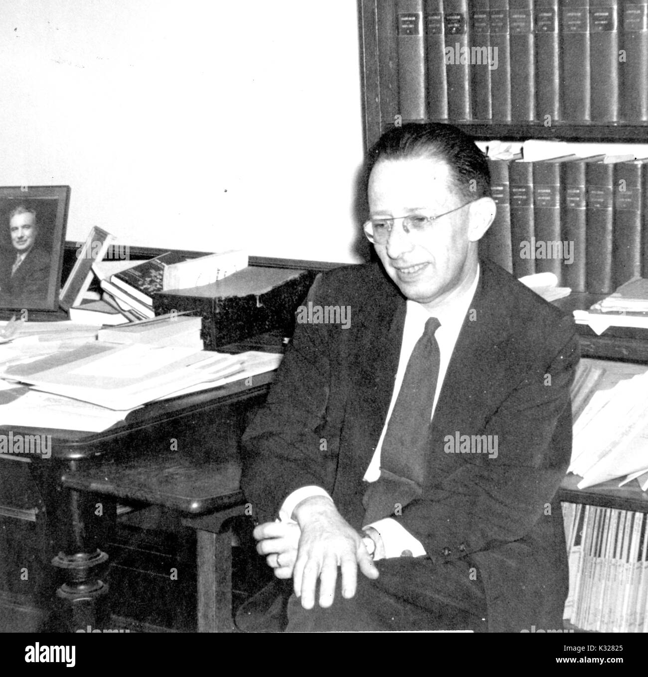 Candid Portrait von Nathan Edelman, Vorsitzender der Abteilung für Romanische Sprachen an der Johns Hopkins University, sitzt in seinem Büro in der Bücherregale, 1955. Stockfoto