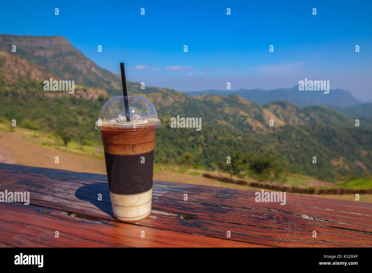 Eine Tasse Eiskaffee auf Holz Tisch mit Blick auf die Berge im Hintergrund. Stockfoto