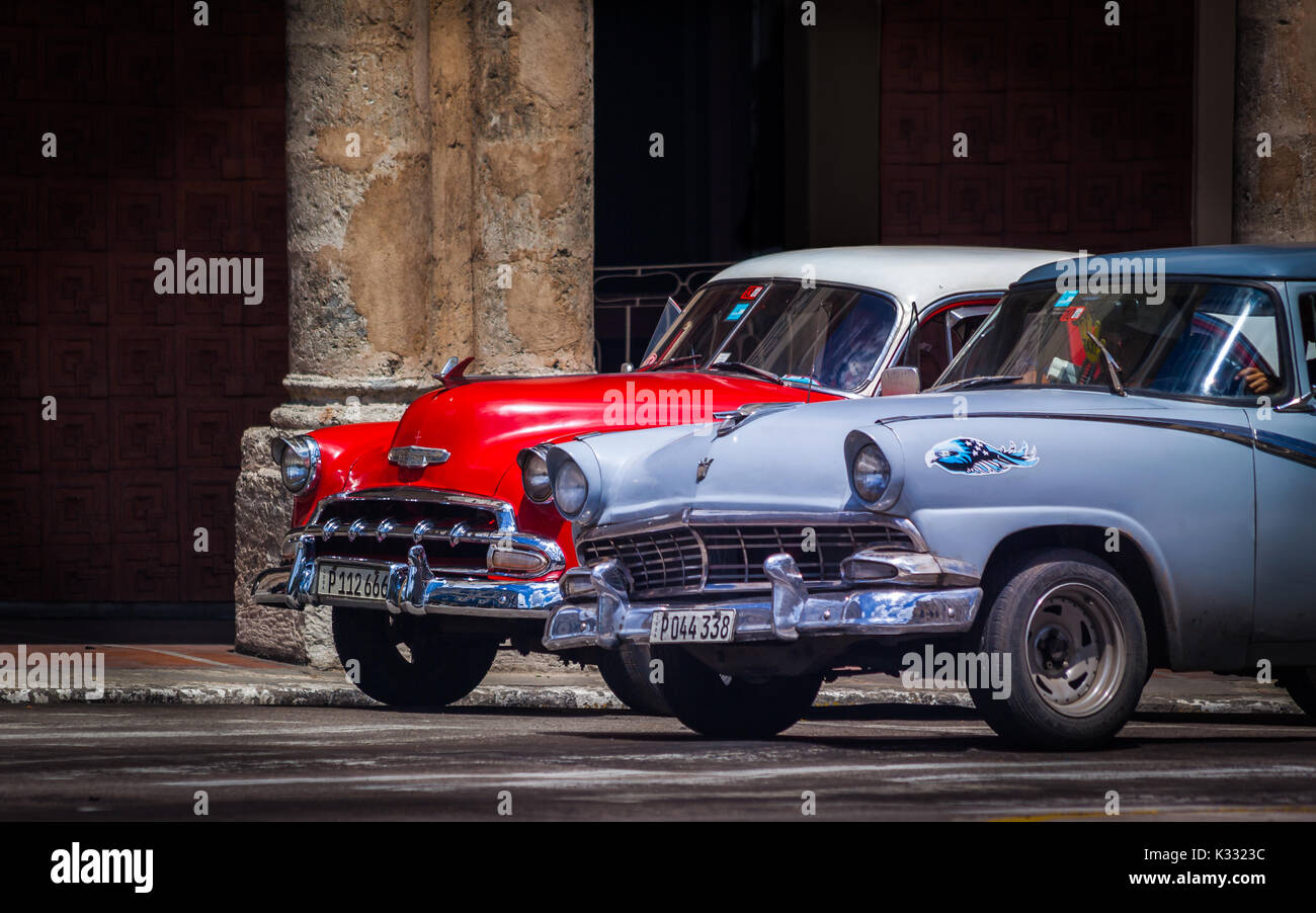 Alte 1950er Autos hielten an einem Ort Kreuzung in Havanna vor einem verfallenen Gebäude aus der Kolonialzeit Stockfoto