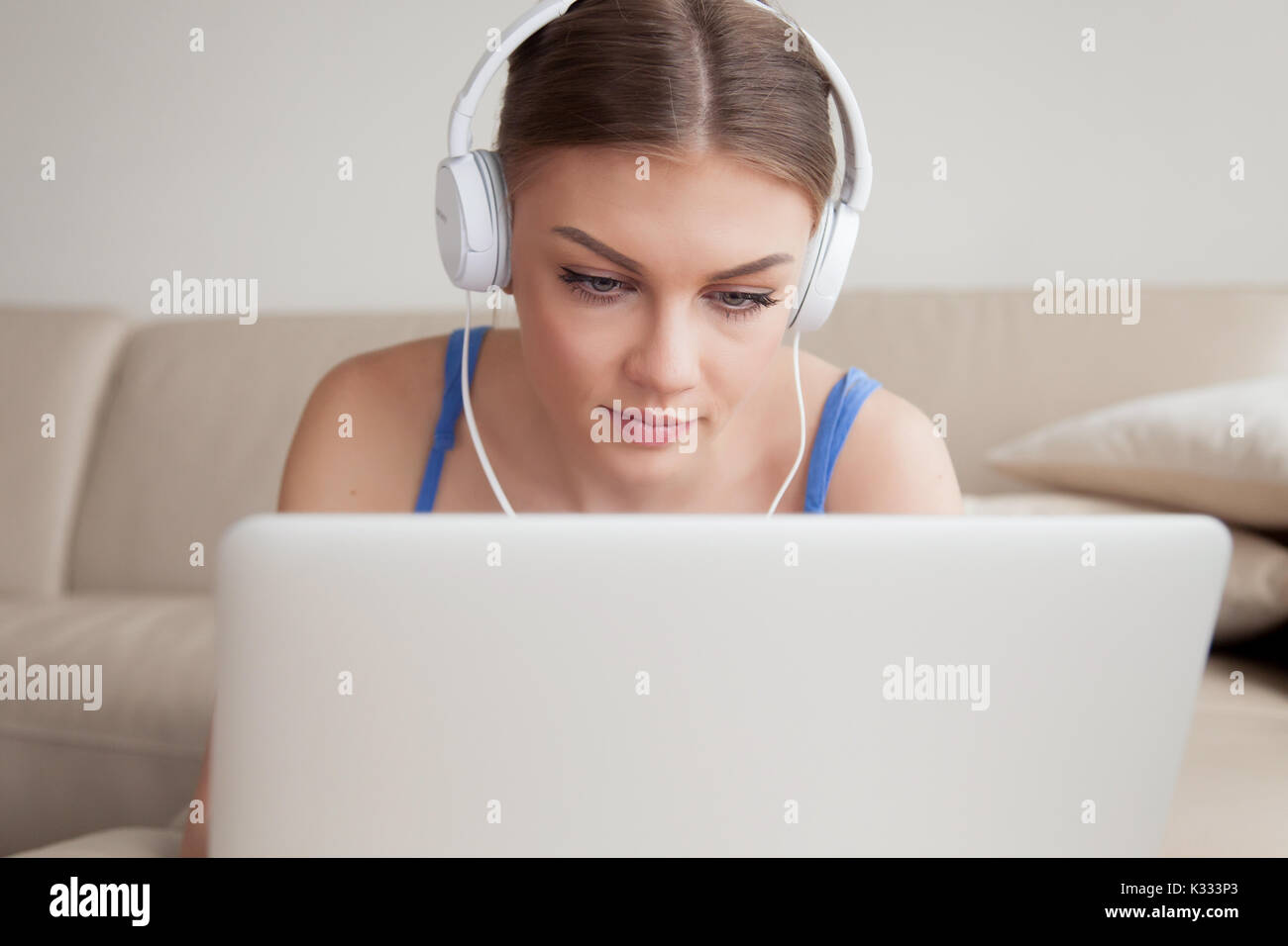 Frau in Kopfhörern über Laptop zu Hause Stockfoto
