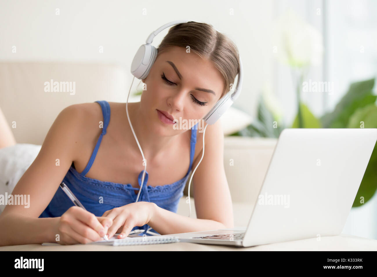 Dame in Kopfhörer Notizen von online Vortrag Stockfoto