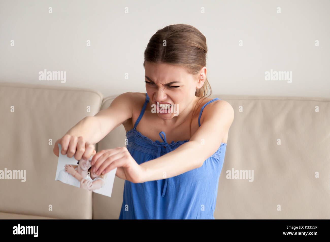 Wütende Frau tränen Papier Foto in zwei Stücke Stockfoto