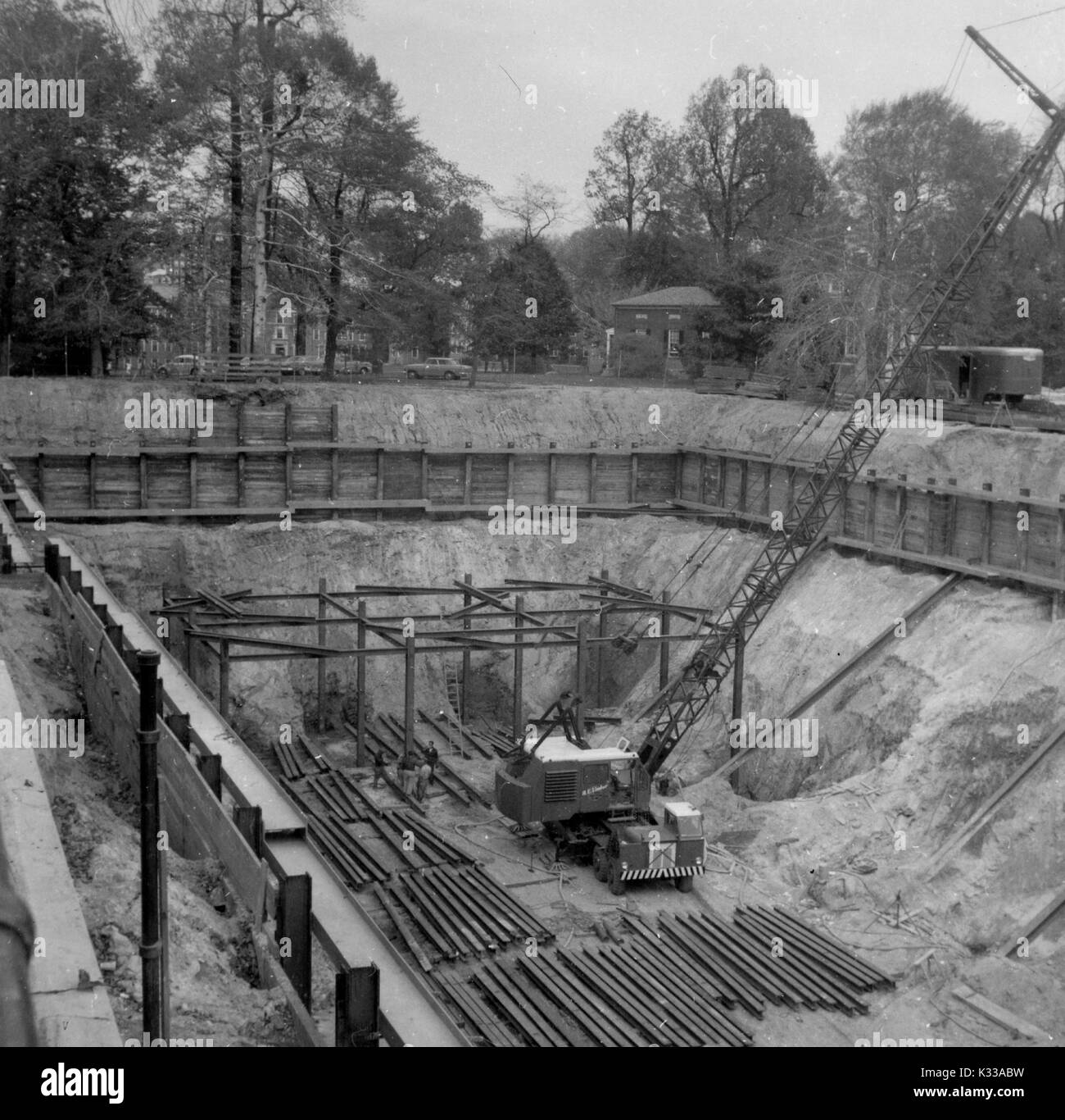 In den frühen Phasen der Konstruktion der Milton S Eisenhower Bibliothek an der Johns Hopkins University, Stahl Arbeit ist in das Fundament des Gebäudes verlegt, mit Bäumen und Campus Gebäude angrenzend an das Projekt Boden, Baltimore, Maryland, Mai, 1962. Stockfoto