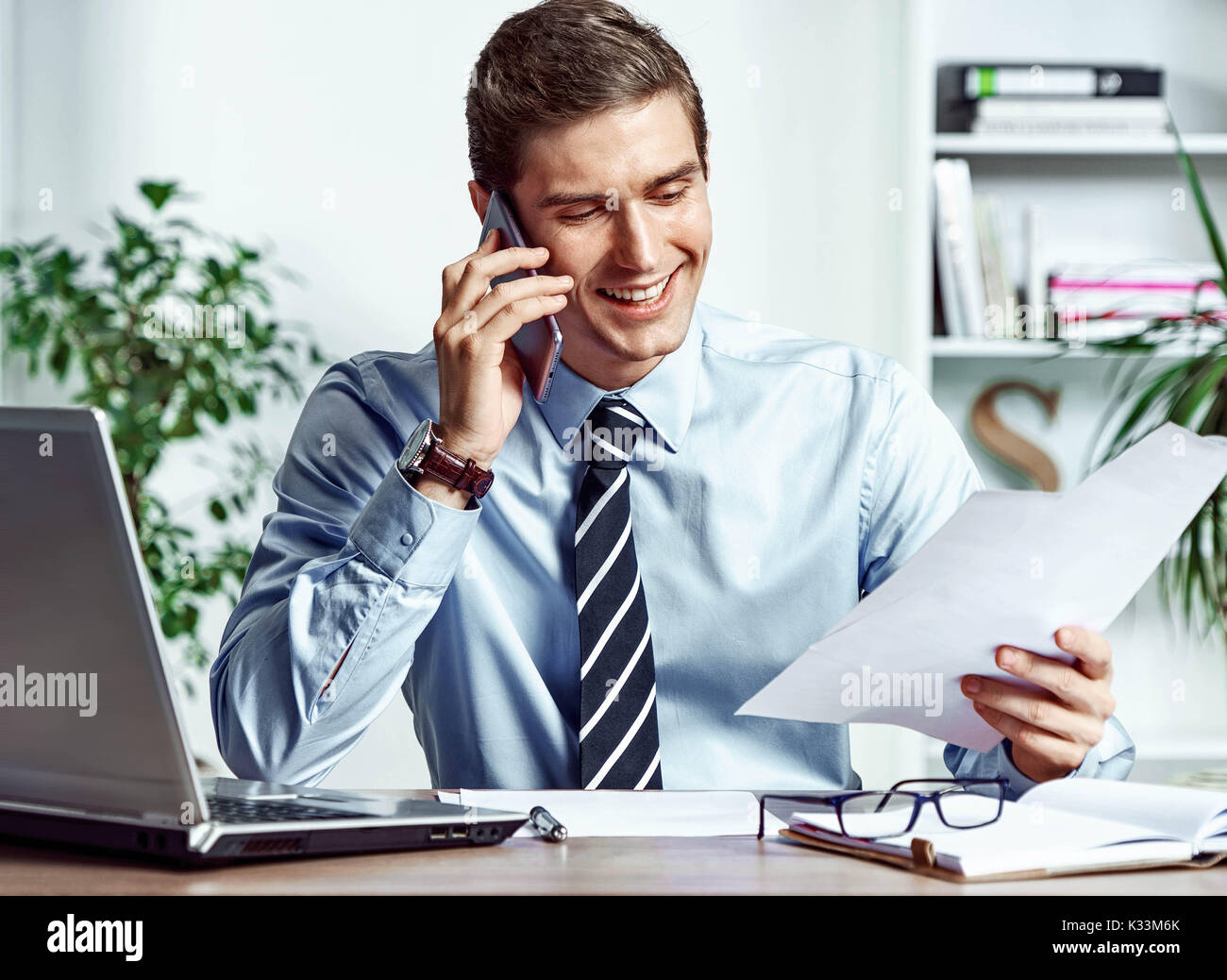 Manager Mann am Telefon zu sprechen und sieht sich die Dokumente. Foto von erfolgreicher Manager arbeiten mit Finanzdaten im Büro. Business Konzept Stockfoto