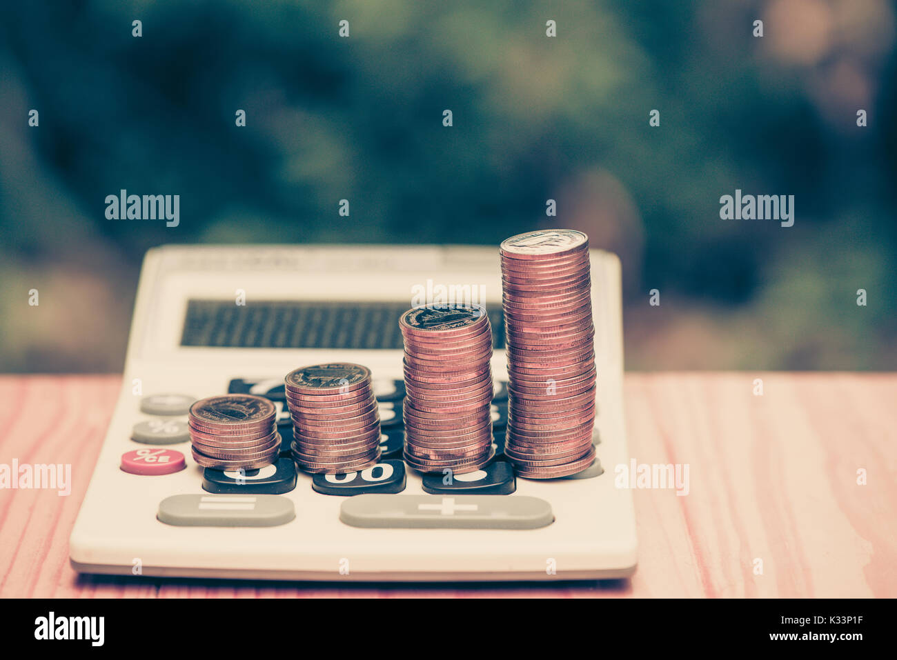 Einsparungen, wachsende Münzen und Taschenrechner auf Holz mit grüner Baum bokeh Hintergrund vintage Ton. Finanzielle Wachstum, Geld sparen, Finanzen Reichtum ein Stockfoto