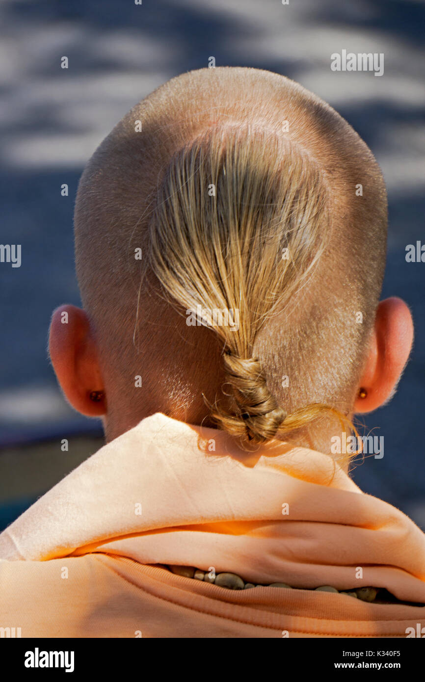 Eine Ansicht von der Rückseite eines männlichen Hare Krishna Anhänger seine ungewöhnliche Frisur zeigt. Im Union Square Park in Manhattan, New York City Stockfoto