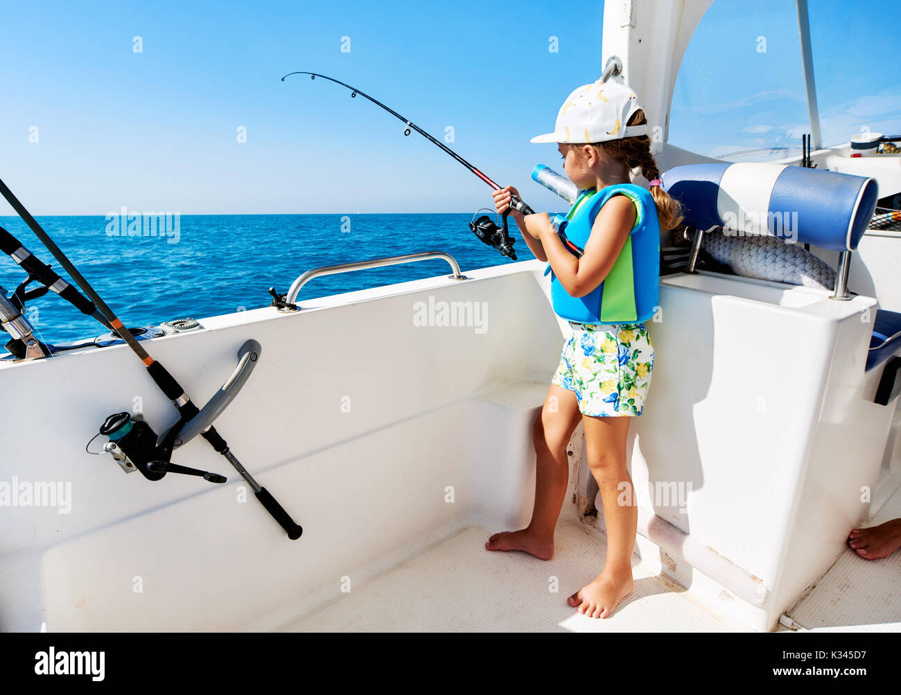 Schönes, kleines Mädchen mit einer Angelrute Fischen vom Boot aus Stockfoto
