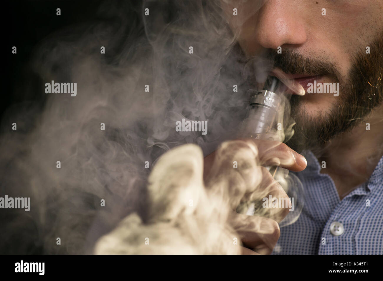 Junger Mann vaping Elektronische Zigarette, E-Zigarette, e cig mit Rauch Wolken. Stockfoto