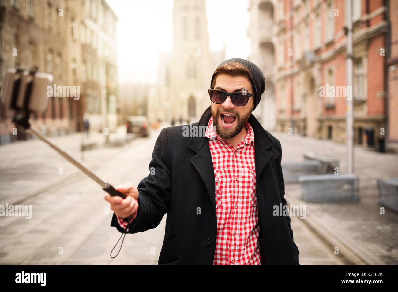 Ein Foto der jungen, trendigen Mann selbst ein Foto von seinem Handy. Er macht lustige Gesichter. Stockfoto