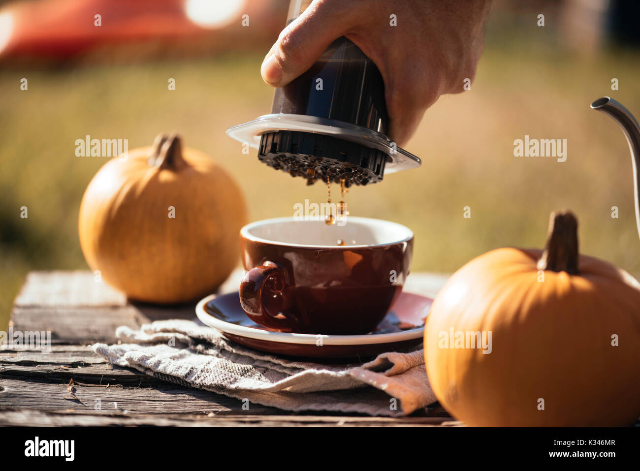 Mann filter Kaffee brühen Outdoor, im Herbst Kaffee Picknick, auf dem alten beschädigt Holztisch Hintergrund. Kaffee tropft in Bewegung in der Pro erfasst Stockfoto