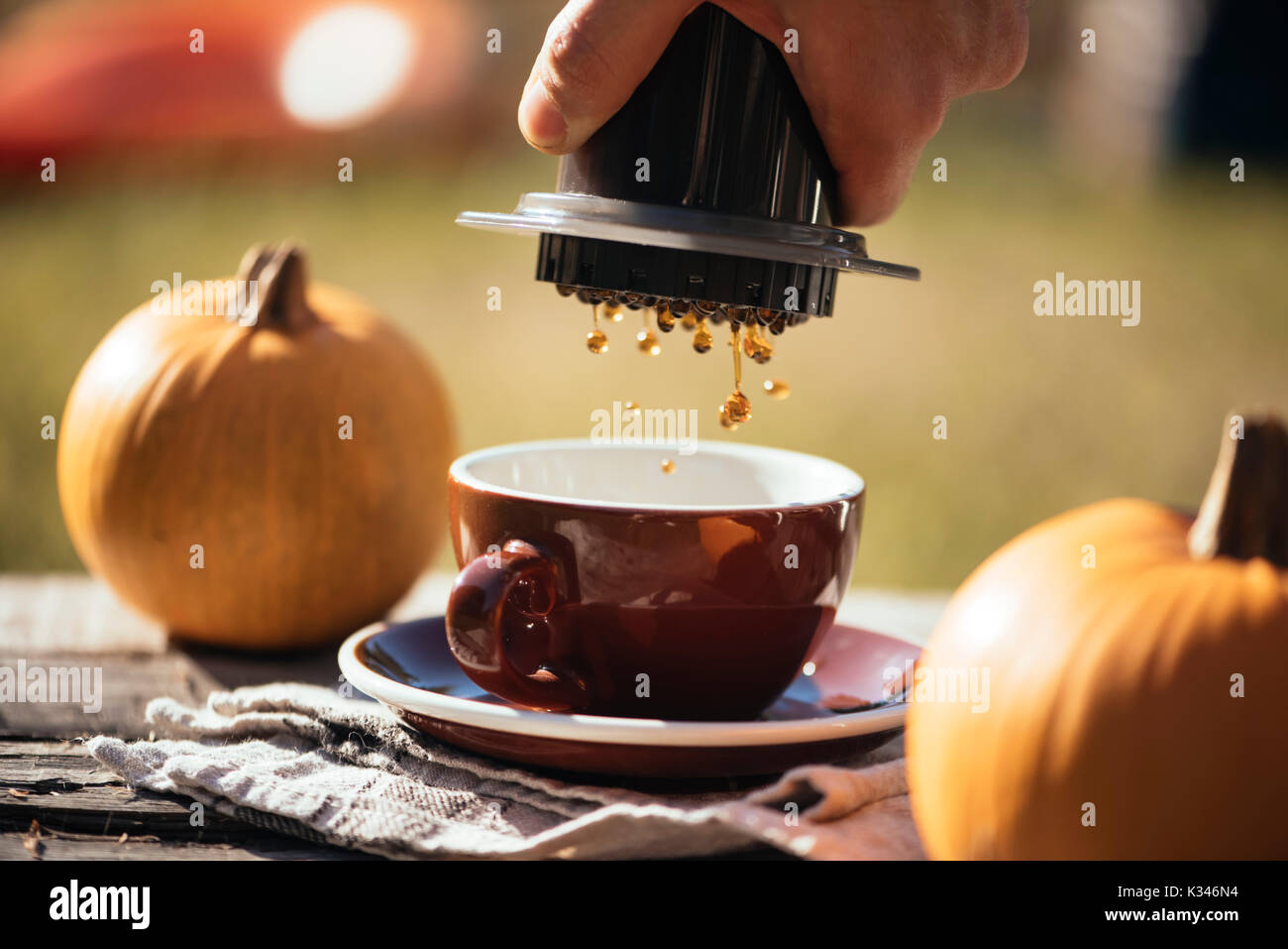 Mann filter Kaffee brühen Outdoor, im Herbst Kaffee Picknick, auf dem alten beschädigt Holztisch Hintergrund. Kaffee tropft in Bewegung in der Pro erfasst Stockfoto
