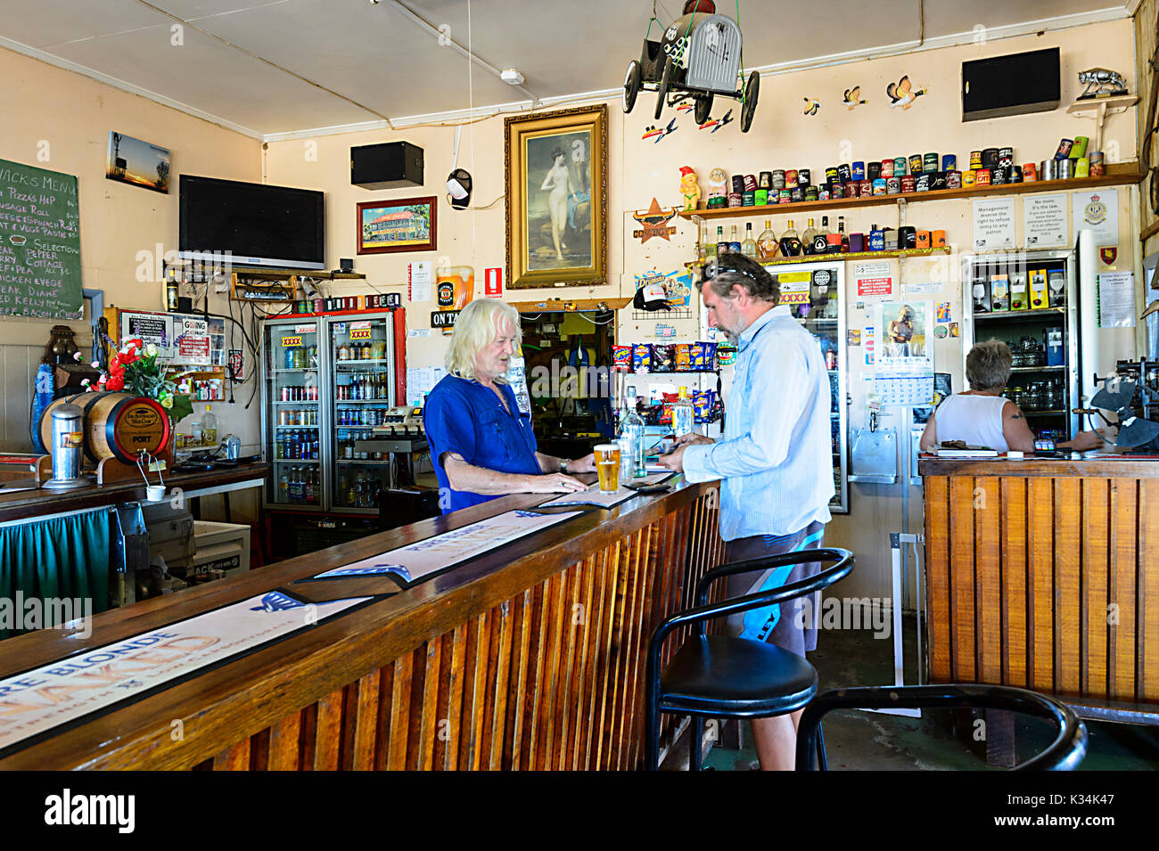Ein Wirt, der einen Kunden in der Bar des historischen Einasleigh Hotels aus der Goldrauschzeit, Einasleigh, Queensland, QLD, Australien, bedient Stockfoto