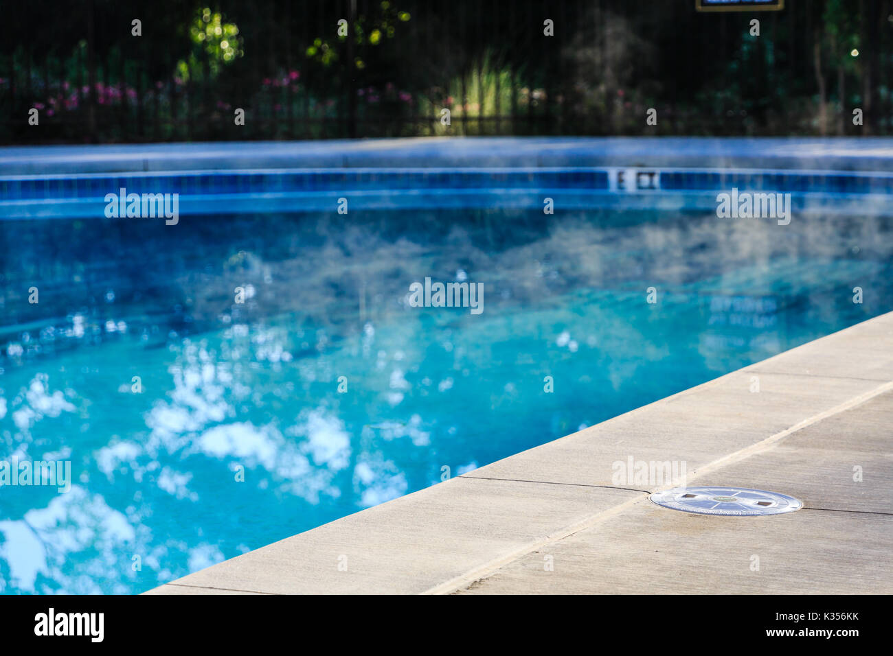 Dampf stieg von beheizten Swimmingpool mit konkreten Deck Stockfoto