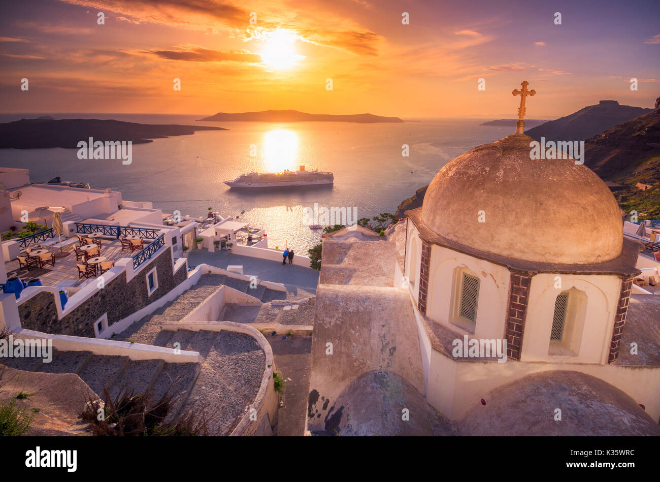 Blick am Abend von Fira, Caldera, Vulkan von Santorini, Griechenland mit Kreuzfahrtschiffen bei Sonnenuntergang. Dramatischer Wolkenhimmel. Stockfoto