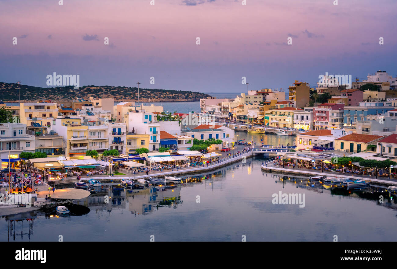 Der See Voulismeni in Agios Nikolaos bei Nacht mit Vollmond, einem malerischen Küstenort mit bunten Gebäude rund um den Hafen im östlichen Teil o Stockfoto