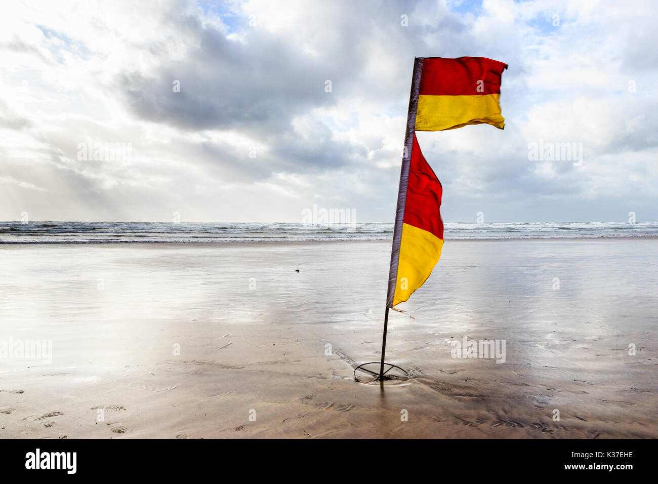 Rot und Gelb Warnung Flagge auf dem Sandstrand in Westward Ho!, Devon, England, UK bei Ebbe an einem bewölkten und windigen Sommer Tag Stockfoto