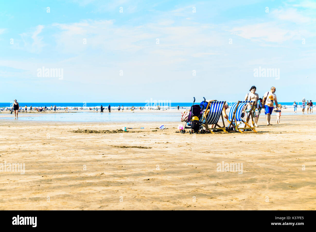 Urlauber gehen zum Strand, um sich im Meer abzukühlen, wenn die Temperaturen steigen, nach Westen Ho!, Devon, Großbritannien Stockfoto