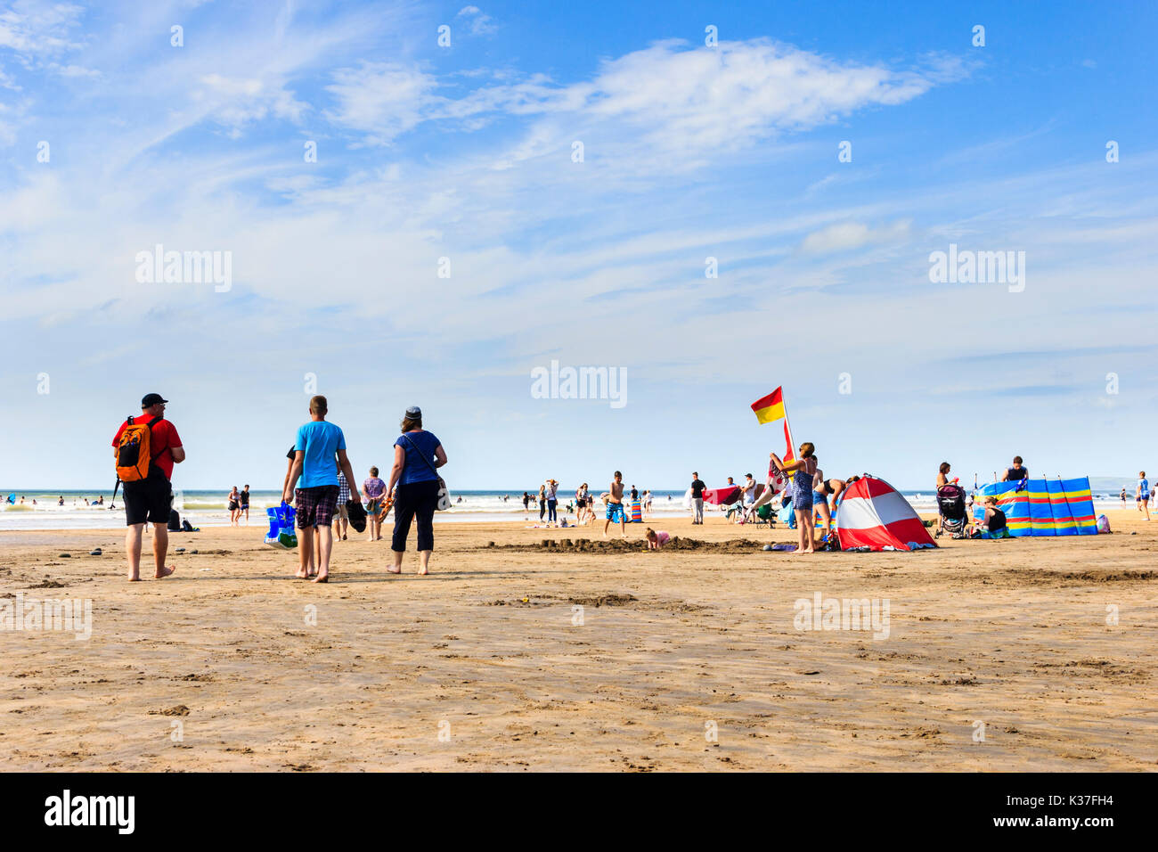 Urlauber gehen zum Strand, um sich im Meer abzukühlen, wenn die Temperaturen steigen, nach Westen Ho!, Devon, Großbritannien Stockfoto