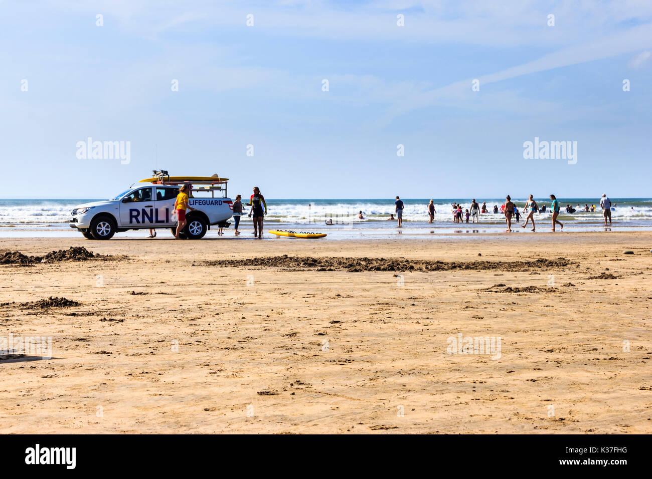 Ein rnli Rettungsschwimmer Fahrzeug und Urlauber auf dem sandigen Strand bei Ebbe an einem sonnigen Tag an Westward Ho!, Devon, England, Großbritannien Stockfoto