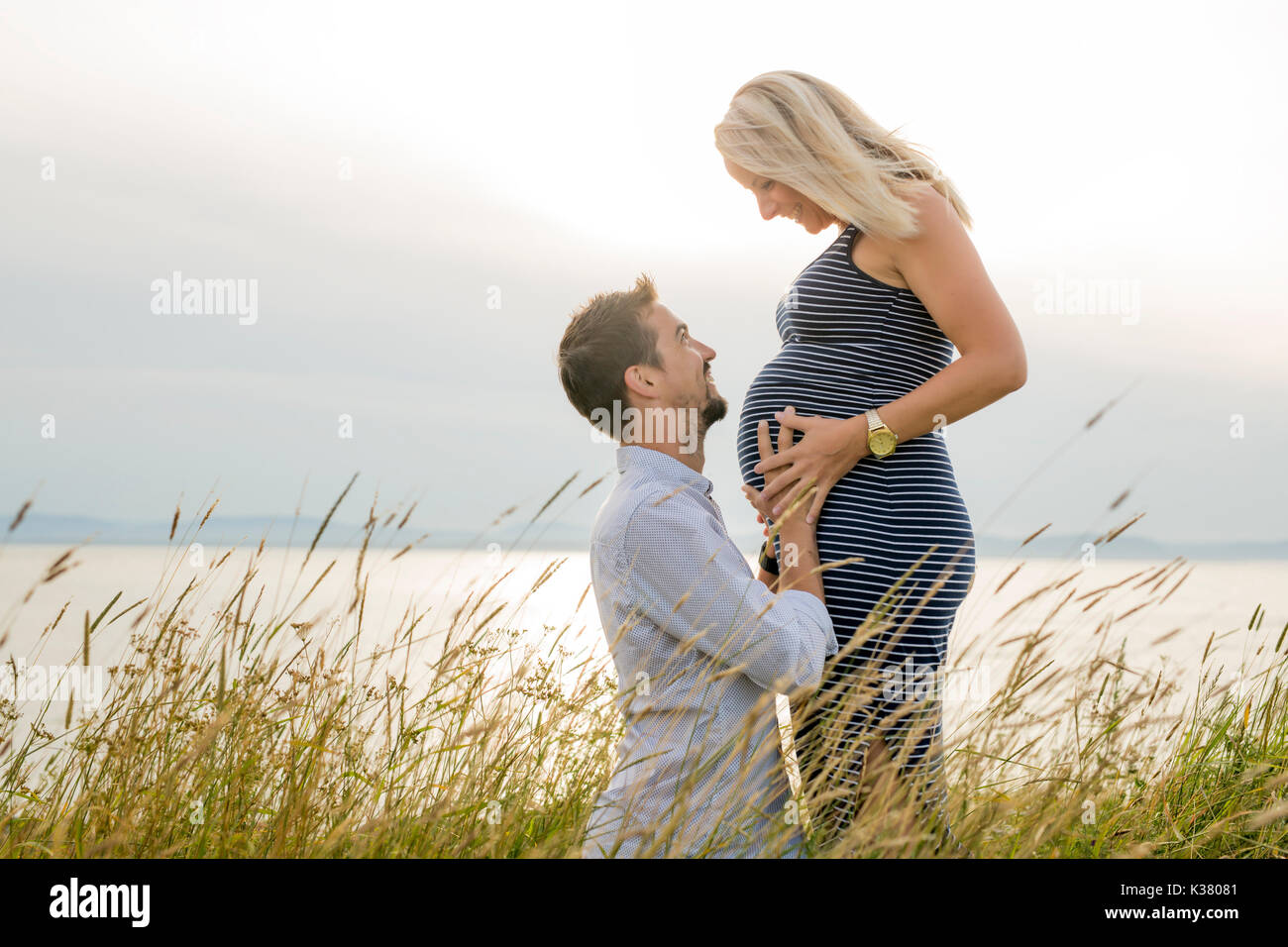 Schwangere Frau am Strand mit Ehemann Spaß Stockfoto