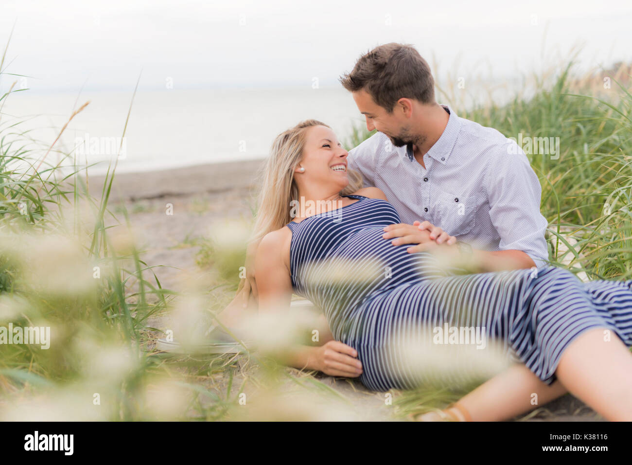 Schwangere Frau am Strand mit Ehemann Spaß Stockfoto