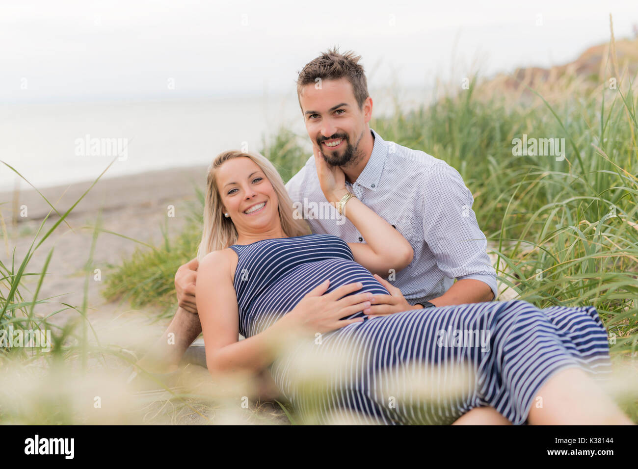 Schwangere Frau am Strand mit Ehemann Spaß Stockfoto
