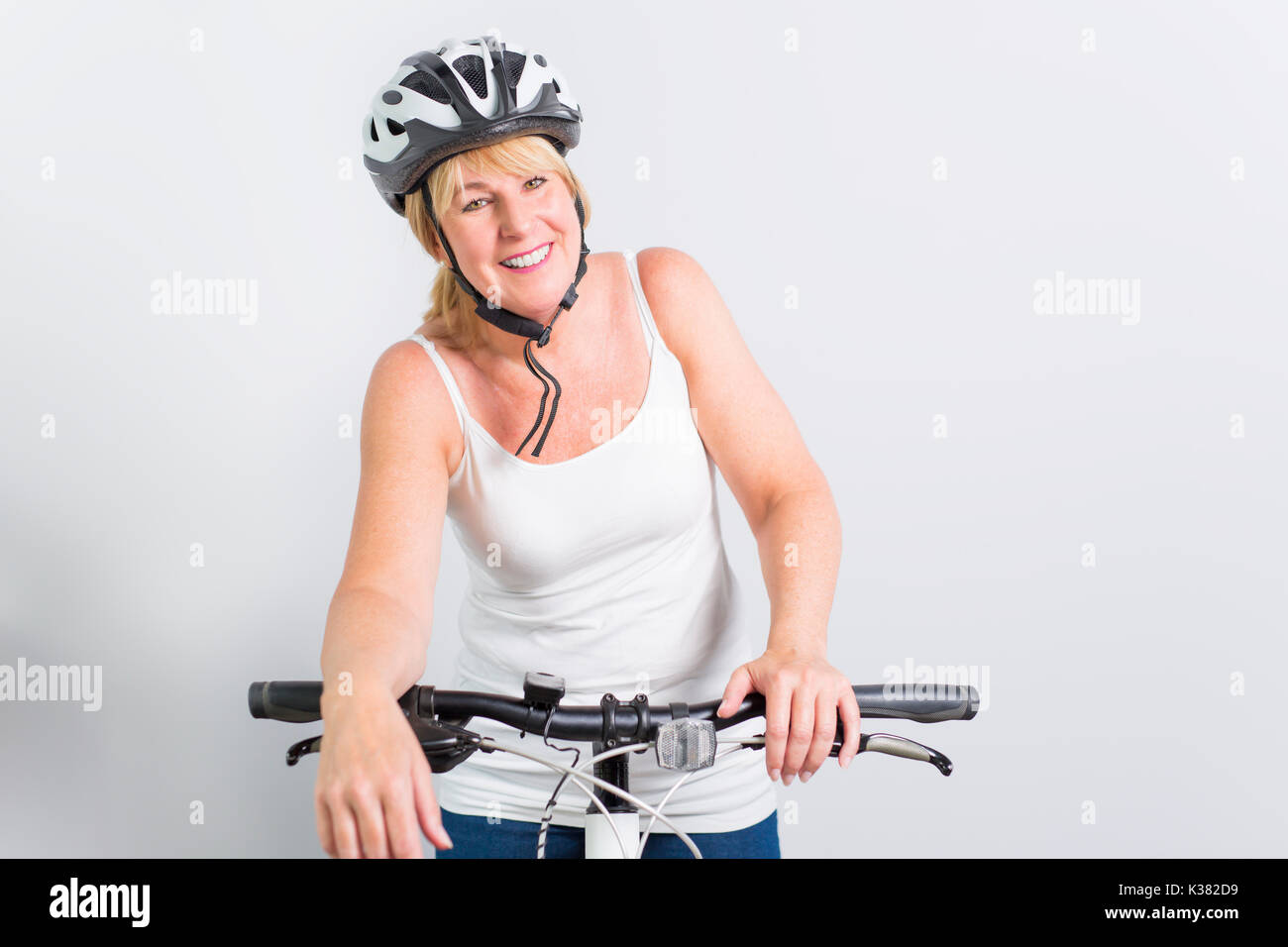 Ältere Frau an der Seite eines Fahrrades im Studio weißer Hintergrund Stockfoto