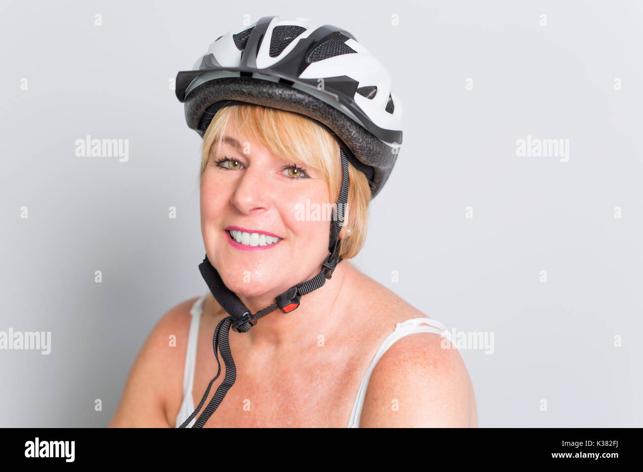 Ältere Frau an der Seite eines Fahrrades im Studio weißer Hintergrund Stockfoto