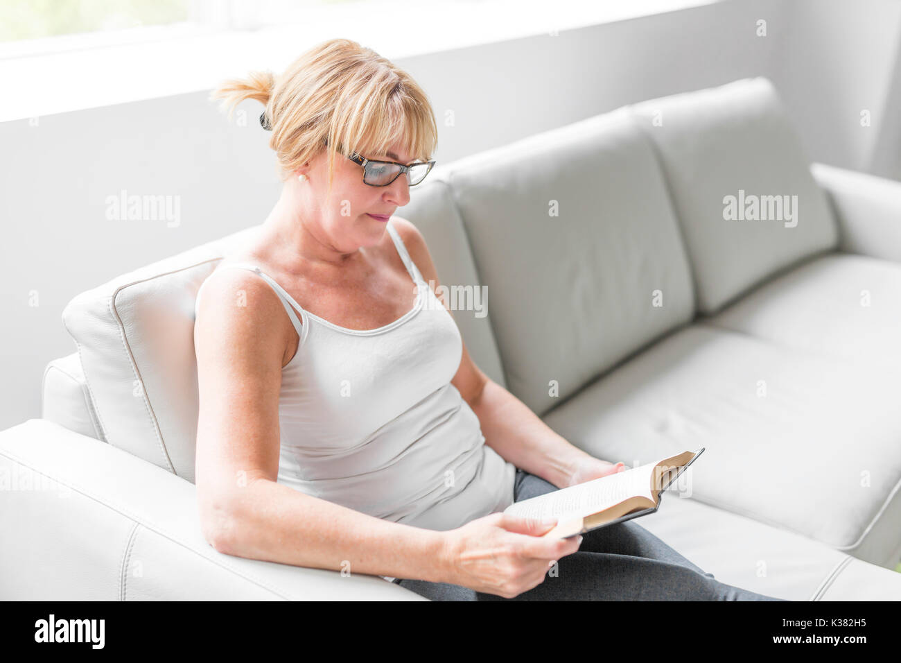 Aufnahme einer reifen Frau ihr Liebling Roman lesen, während zu Hause im Wohnzimmer. Stockfoto