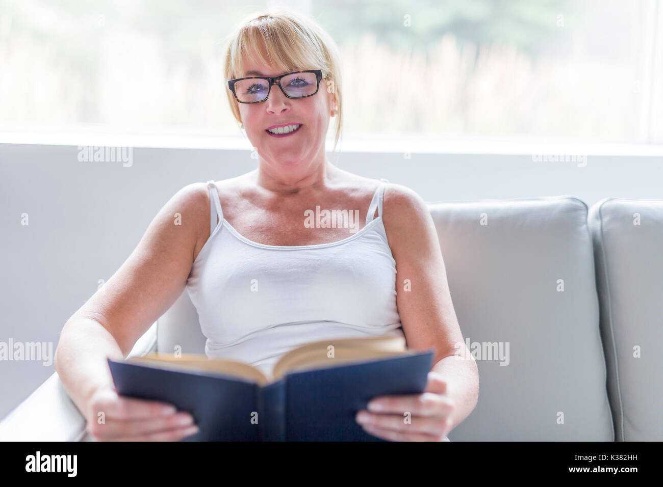 Aufnahme einer reifen Frau ihr Liebling Roman lesen, während zu Hause im Wohnzimmer. Stockfoto