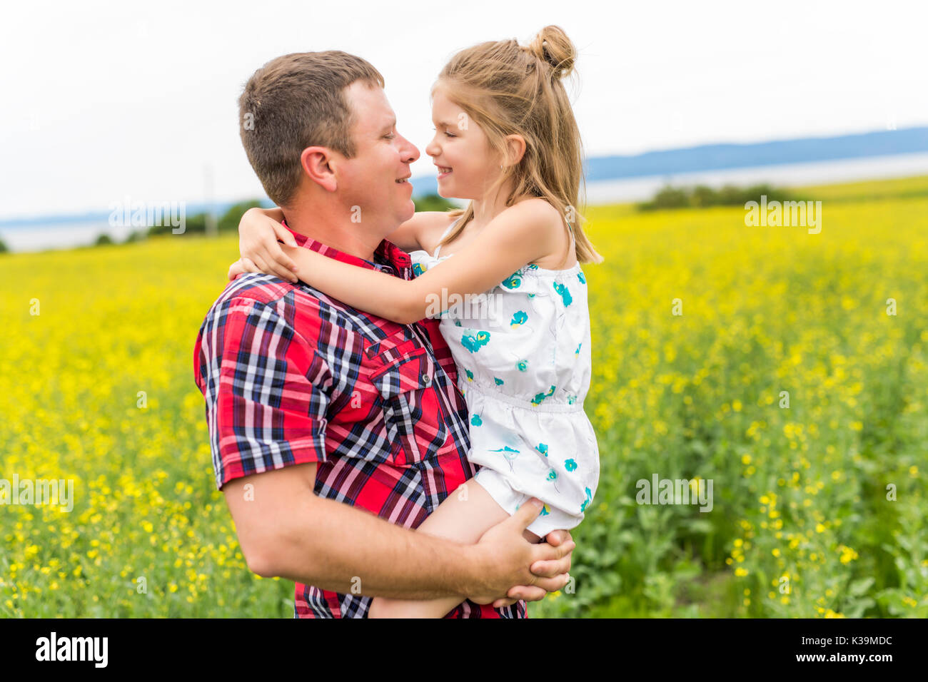 Glückliche Familie Vater und Kind Tochter auf gelben Blumen auf Natur im Sommer Stockfoto