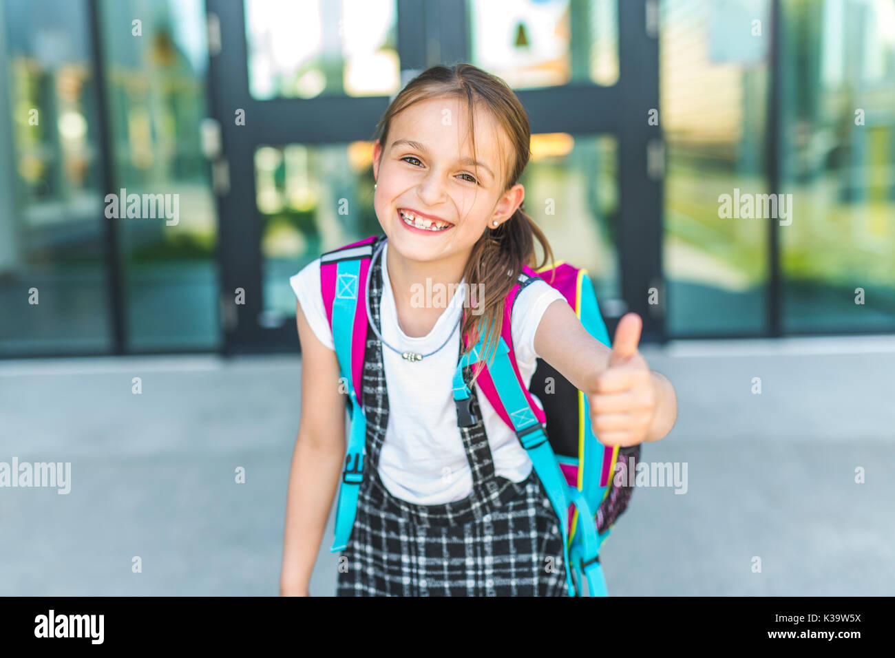 Mädchen außerhalb der Schule mit Tasche stehend Stockfoto