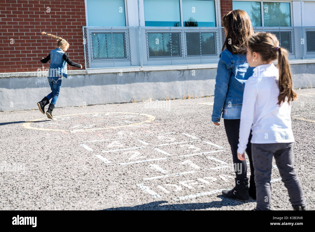Hopscotch auf dem Schulhof mit Freunden gemeinsam spielen Stockfoto