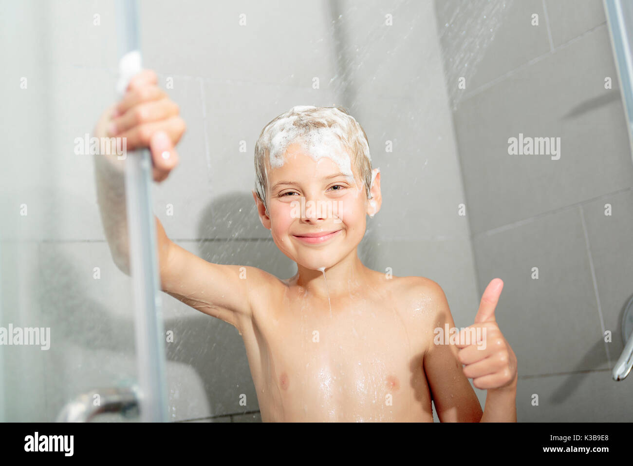 Happy Teen boy waschen Kopf in der Dusche im Badezimmer Stockfoto