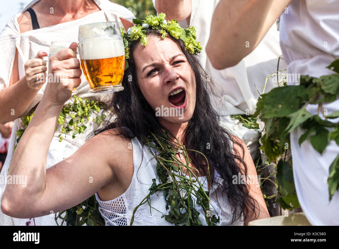 Tschechisches Bierfest, Junge Frau trinkt Bier Tschechische Republik genießt Bier, Frau jubelt Bier Frau Wreath of Hop Stockfoto