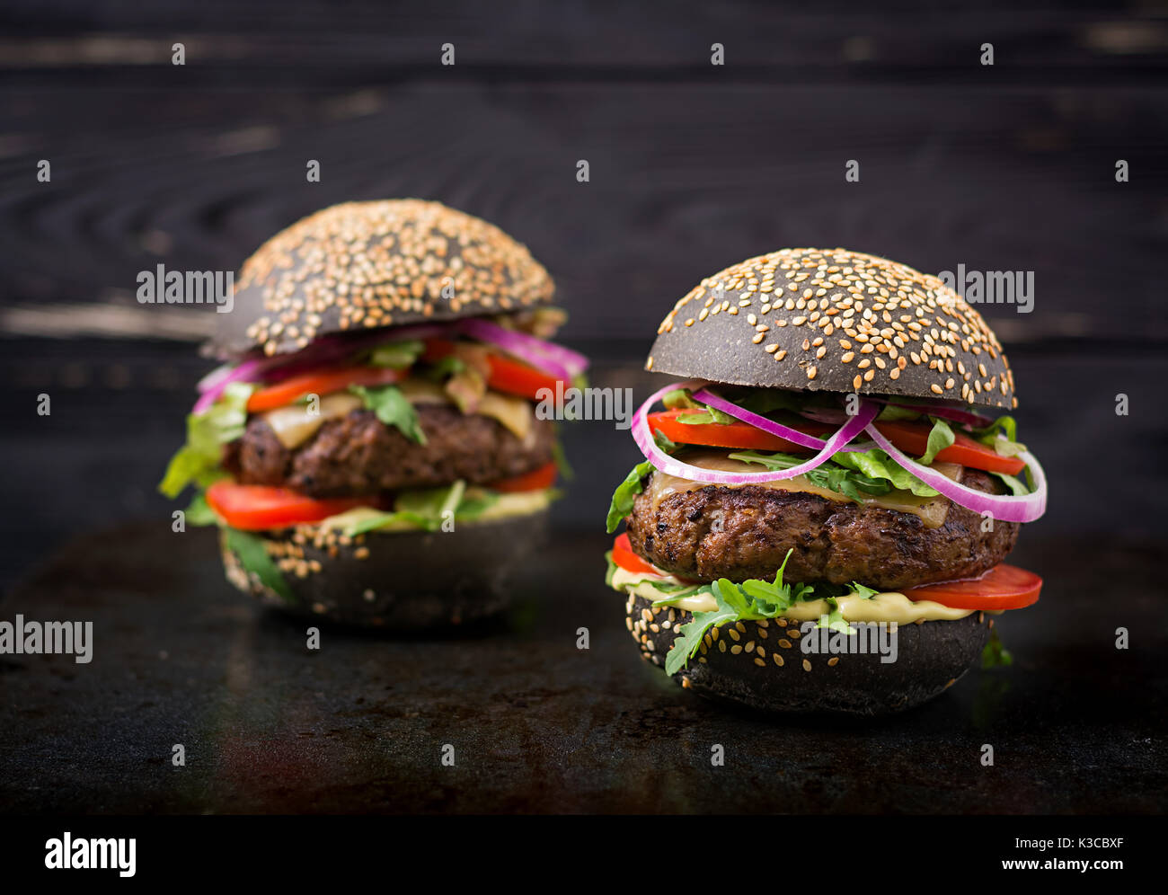 Schwarz big Sandwich - schwarz Hamburger mit saftigen Beef Burger, Käse, Tomaten und Zwiebel rot auf schwarzem Hintergrund Stockfoto