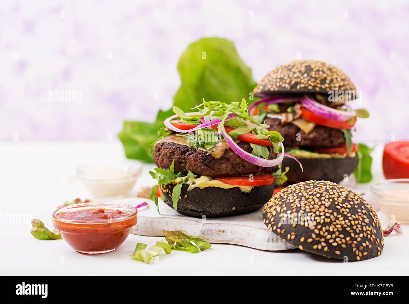 Schwarz big Sandwich - schwarz Hamburger mit saftigen Beef Burger, Käse, Tomaten und Zwiebel rot auf hellem Hintergrund. Stockfoto