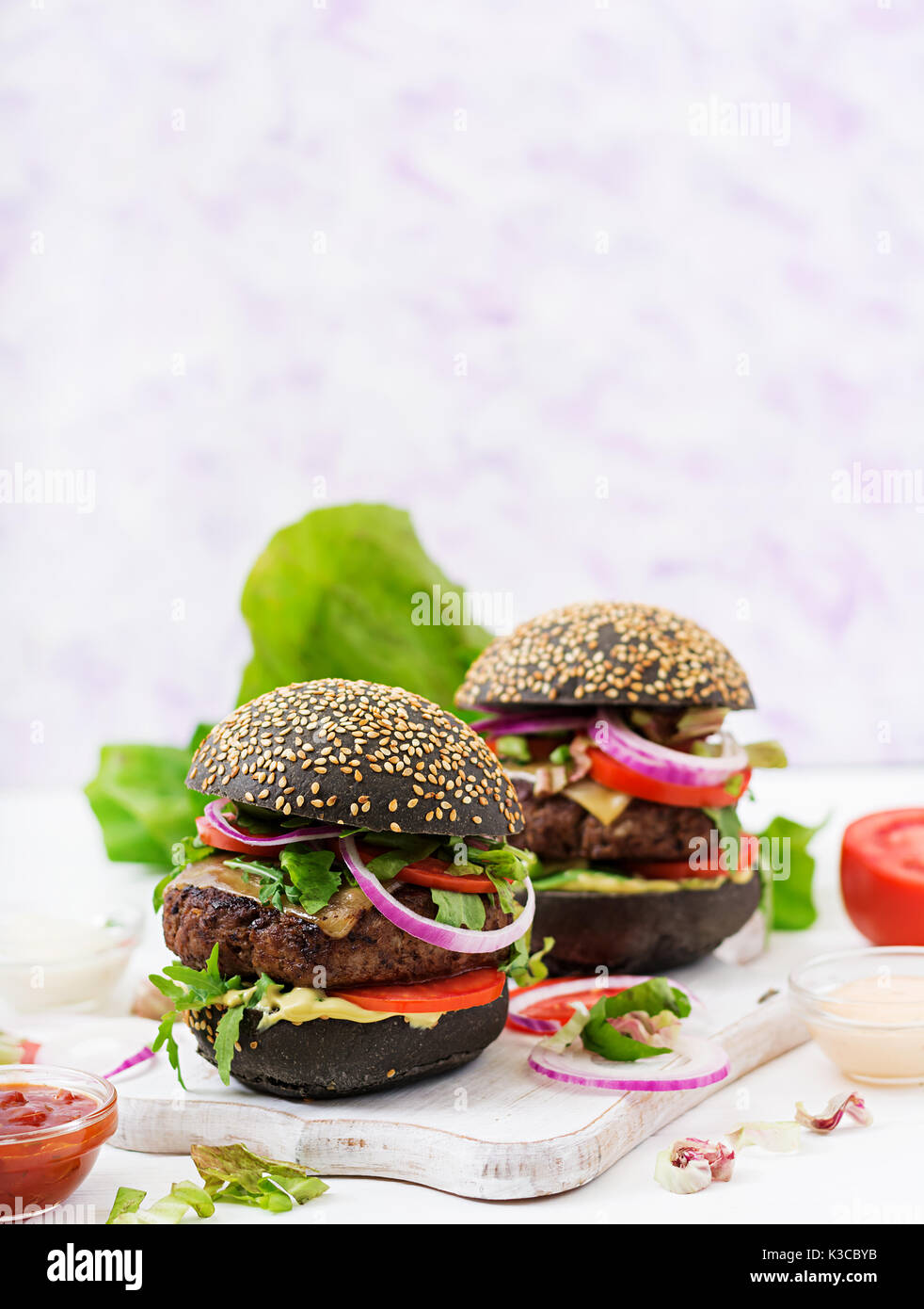 Schwarz big Sandwich - schwarz Hamburger mit saftigen Beef Burger, Käse, Tomaten und Zwiebel rot auf hellem Hintergrund. Stockfoto