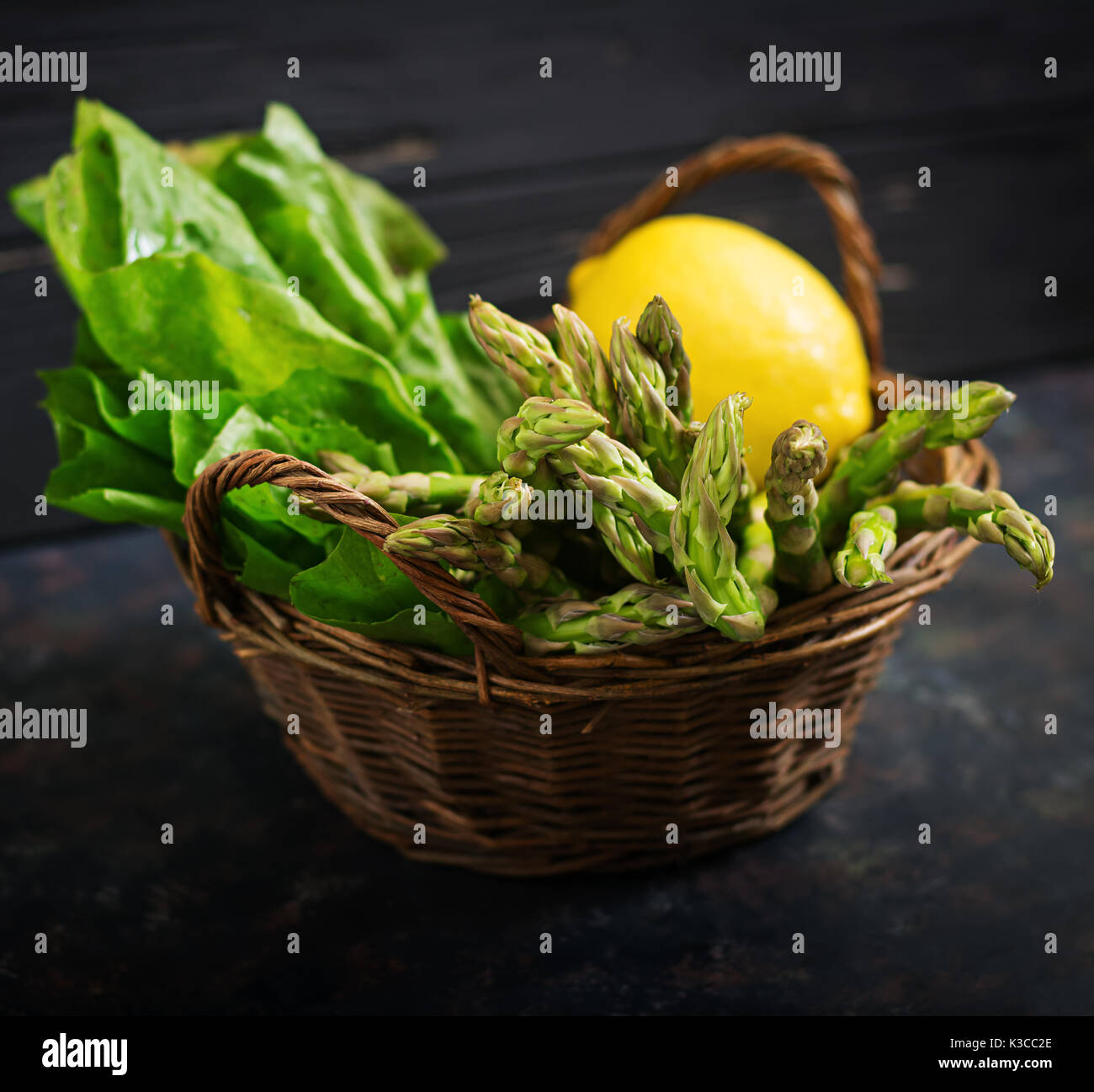 Frischer Spargel im Warenkorb auf dunklem Hintergrund. Stockfoto