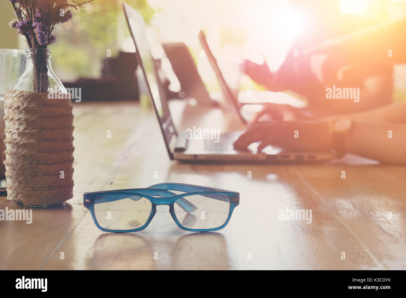 Brillen im Vordergrund, nicht erkanntes Geschäftsleute interaktiv mit Laptop im Hintergrund Stockfoto
